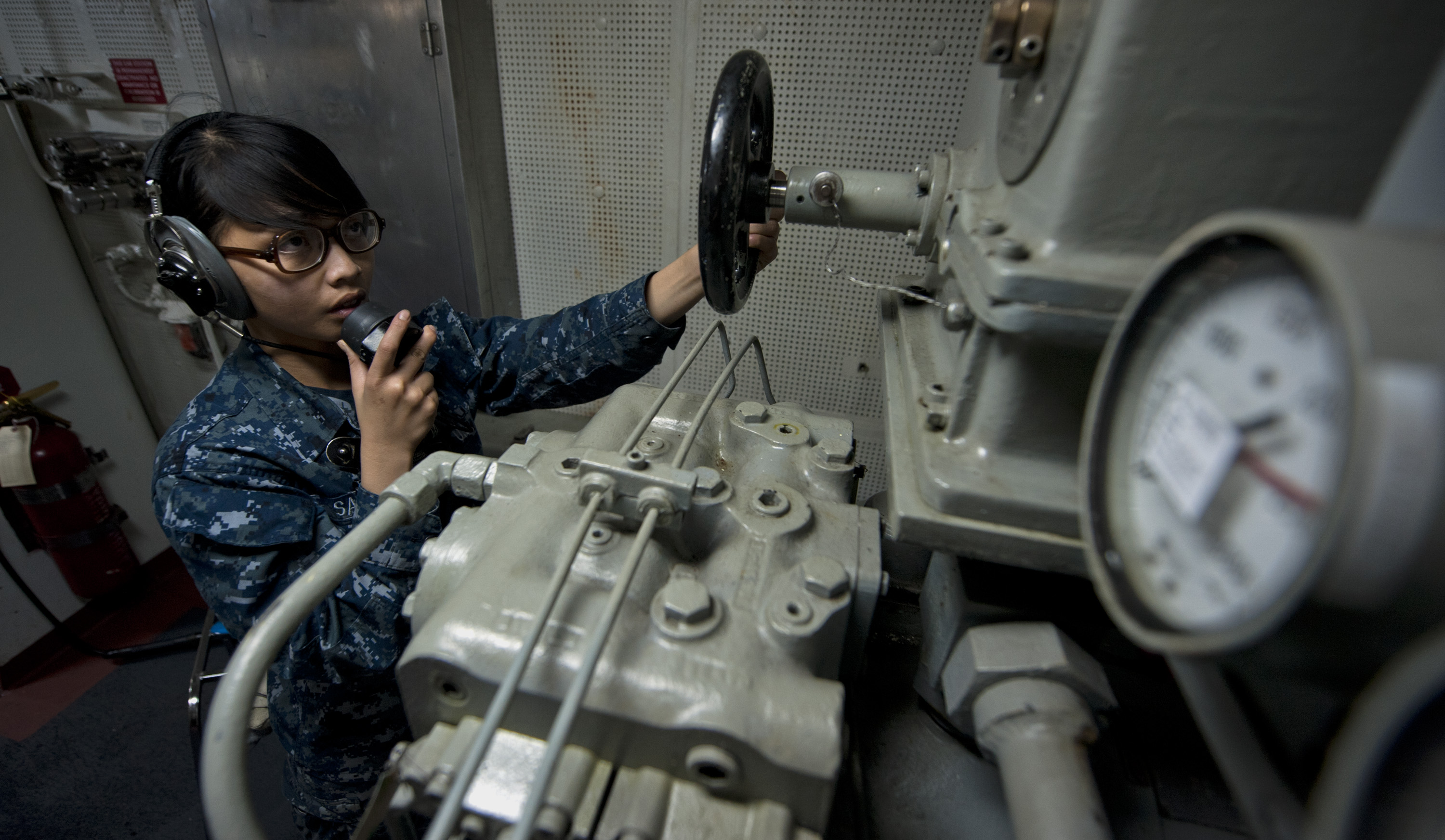 US Navy 111003-N-TU221-044 Seaman Mafe Sabar mans a sound-powered telephone inside the aft steering engine room aboard the Nimitz-class aircraft ca