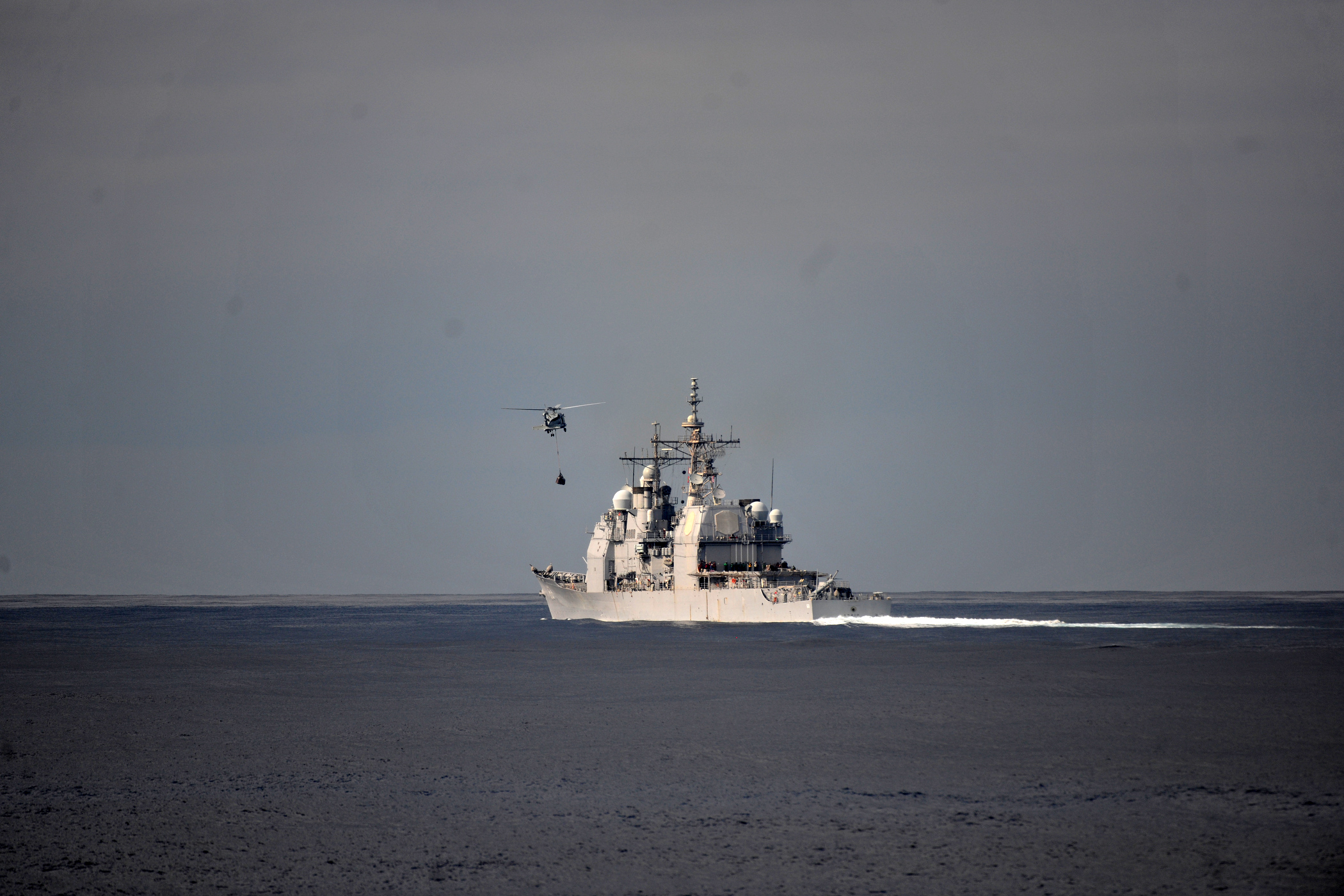 US Navy 111129-N-YZ751-198 A helicopter approaches a guided-missile cruiser