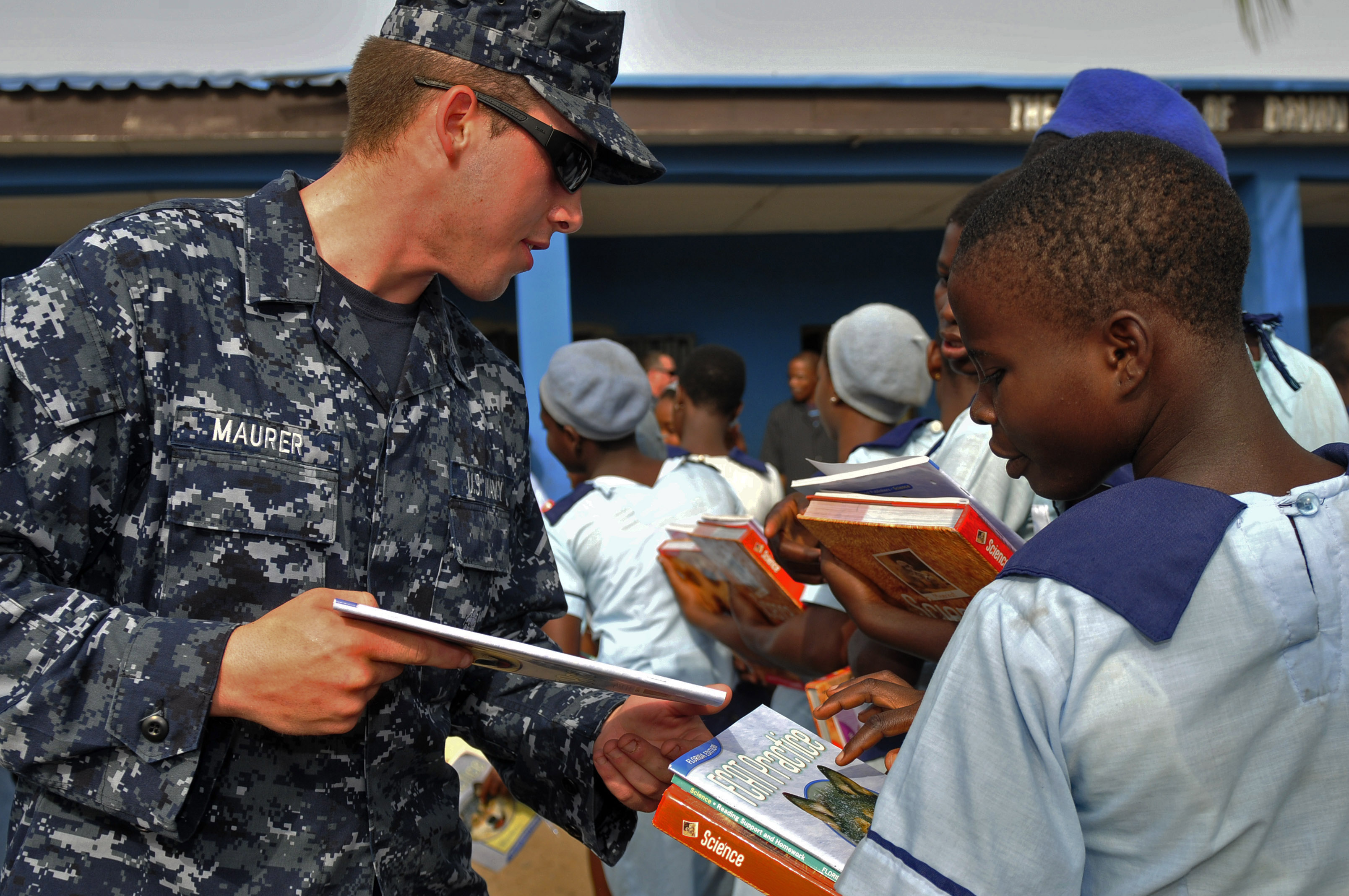 US Navy 120216-N-IZ292-060 Boatswain's Mate Seaman Joshua Maurer, assigned to the guided-missile frigate USS Simpson (FFG 56), hands books to schoo