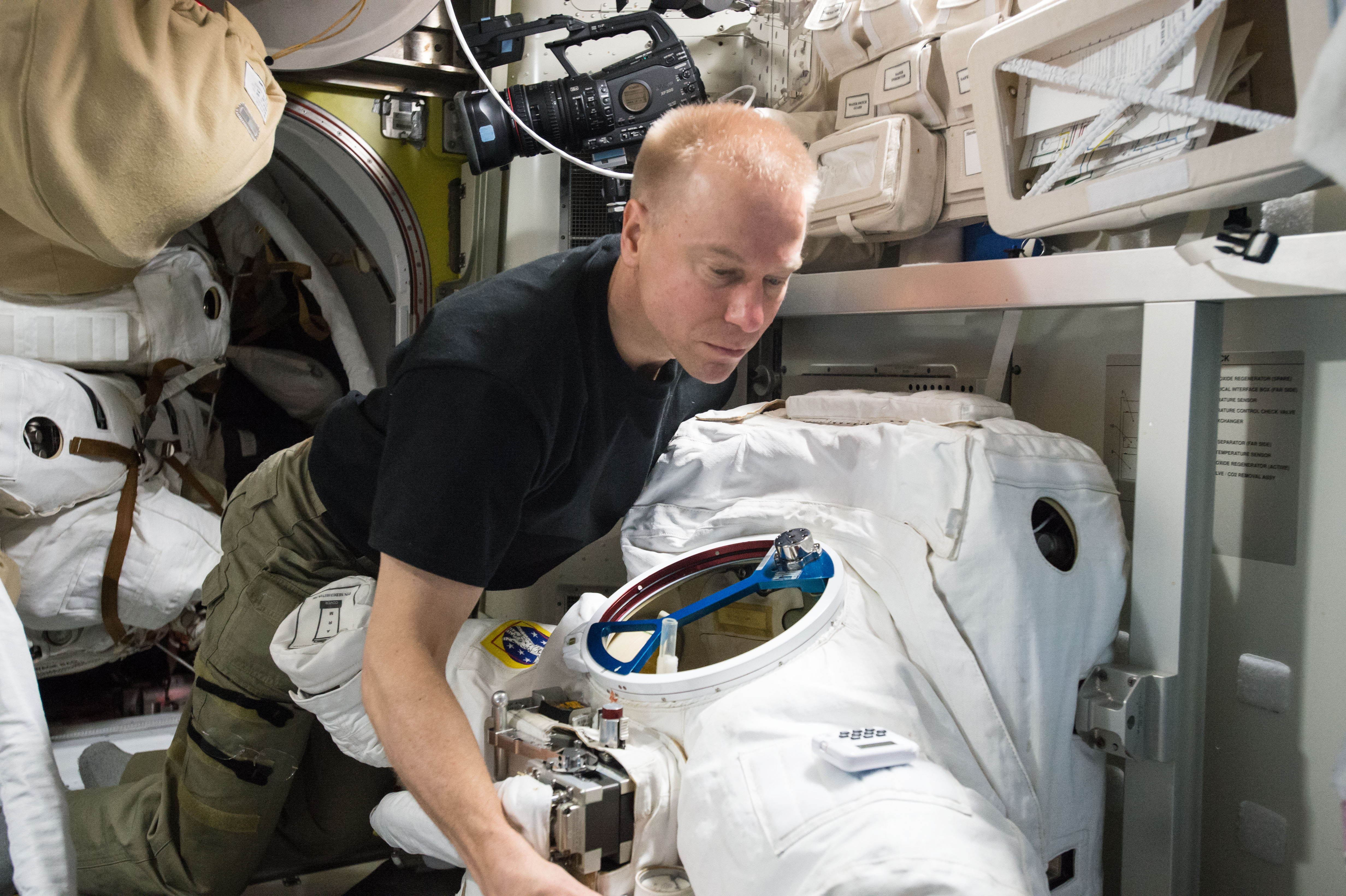 ISS-47 Tim Kopra with space suits in the Quest airlock