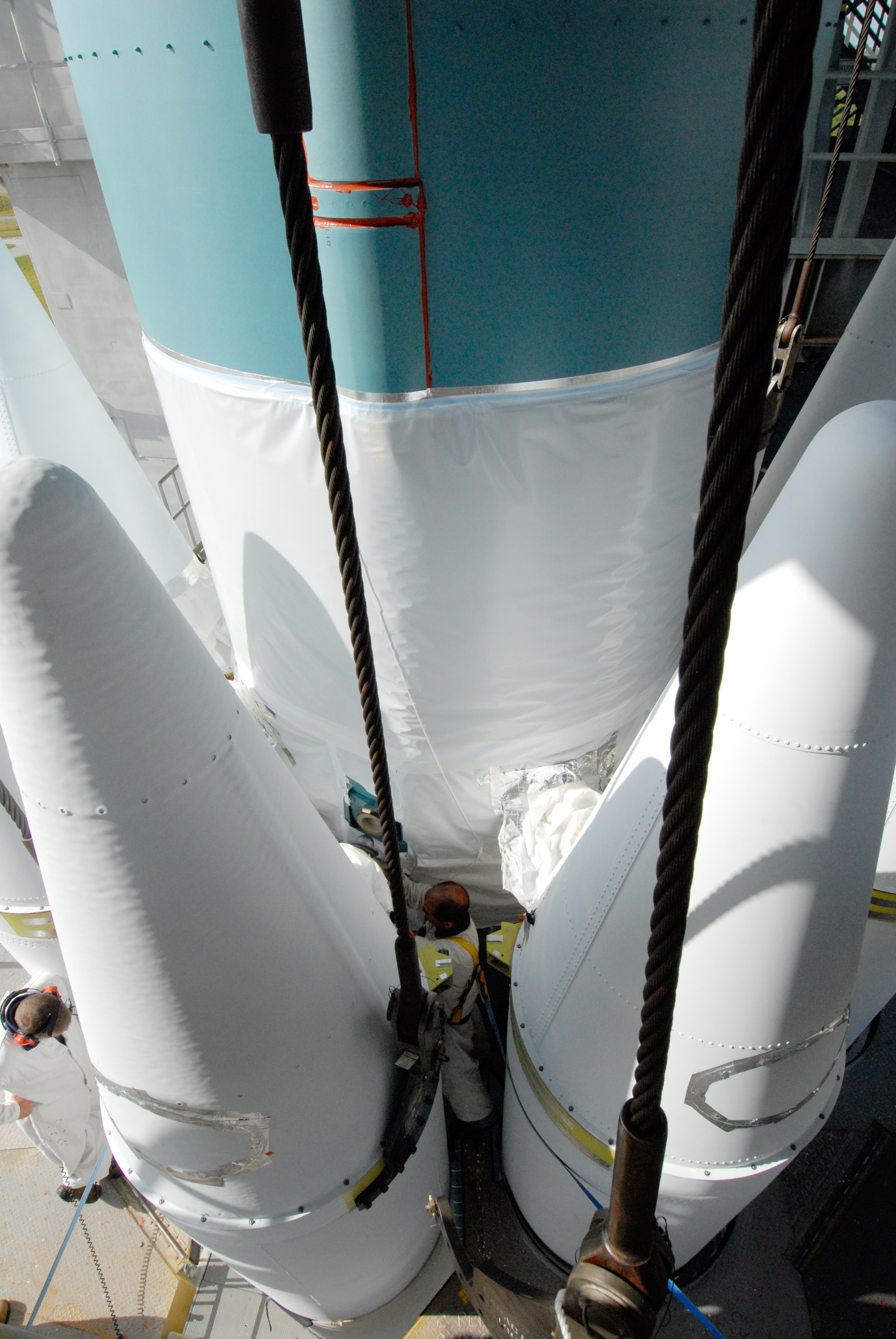 Technicans between heavy booster and Delta II first stage