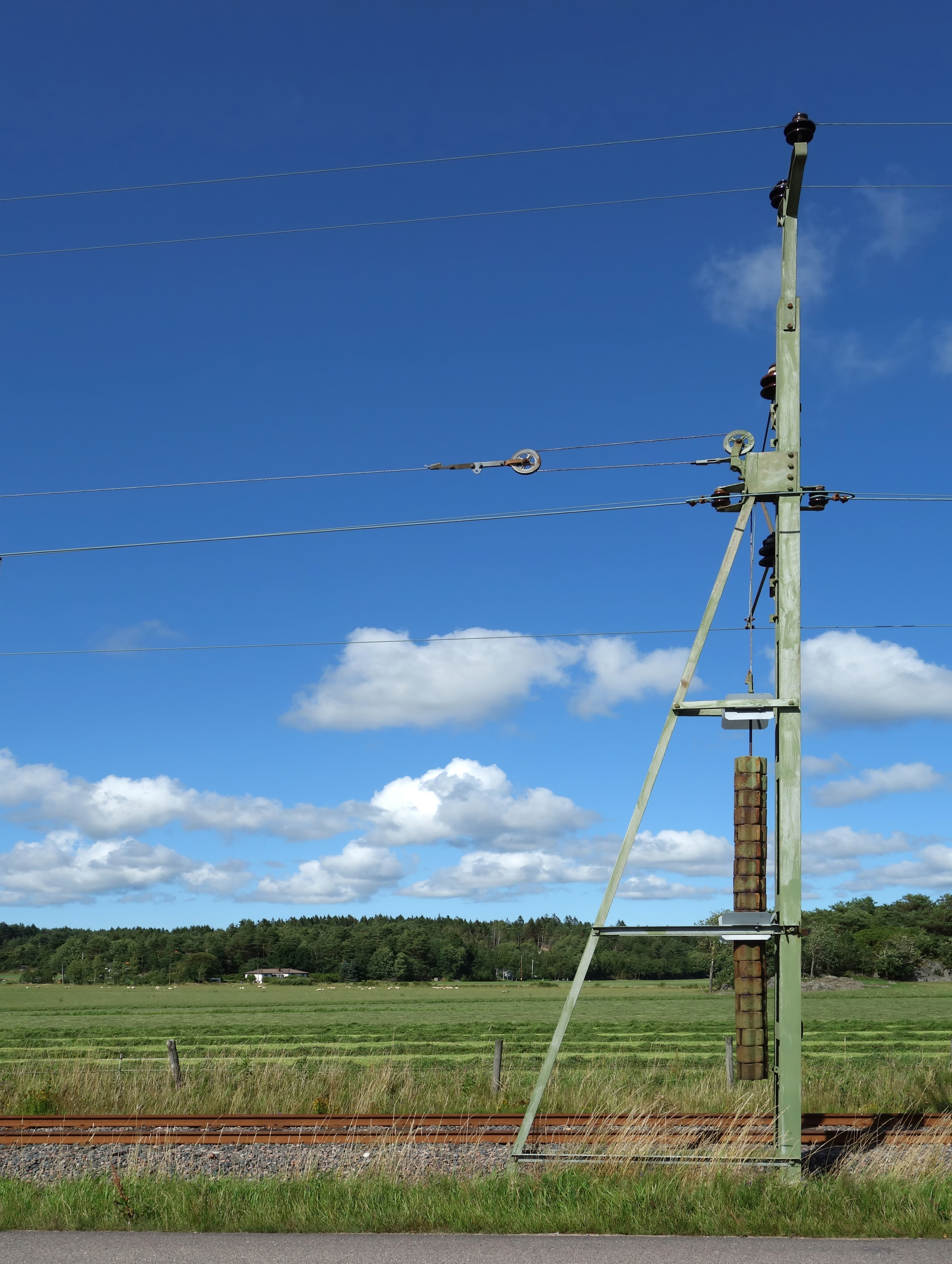Pole with tension weight for overhead lines
