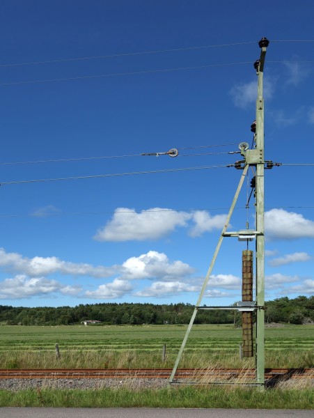 Pole with tension weight for overhead lines