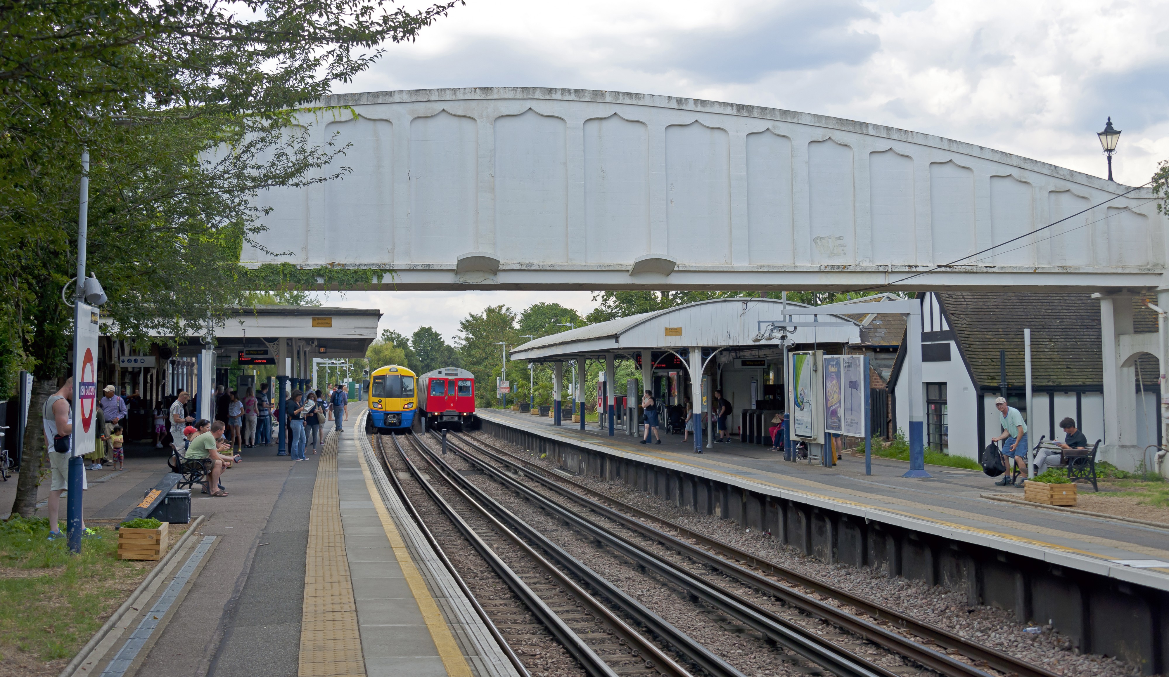 London Overground and Underground trains at Kew Gardens, with footbridge